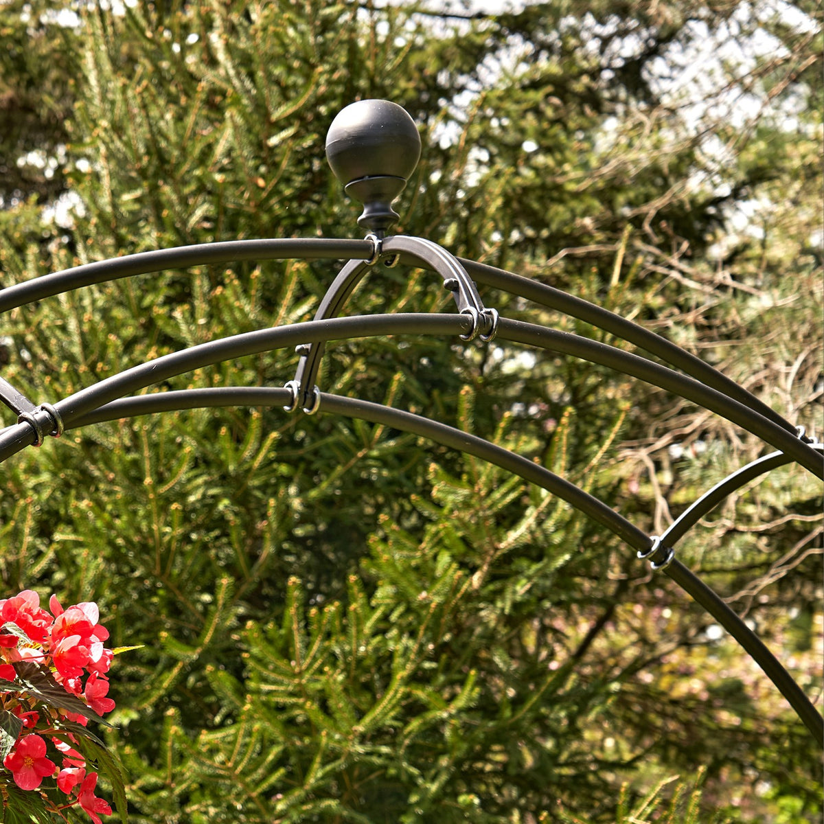 Close view of the matte black arch's curved top rails and round finial