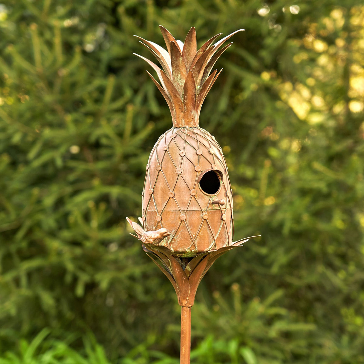 Full pineapple-shaped birdhouse stake shown against green foliage