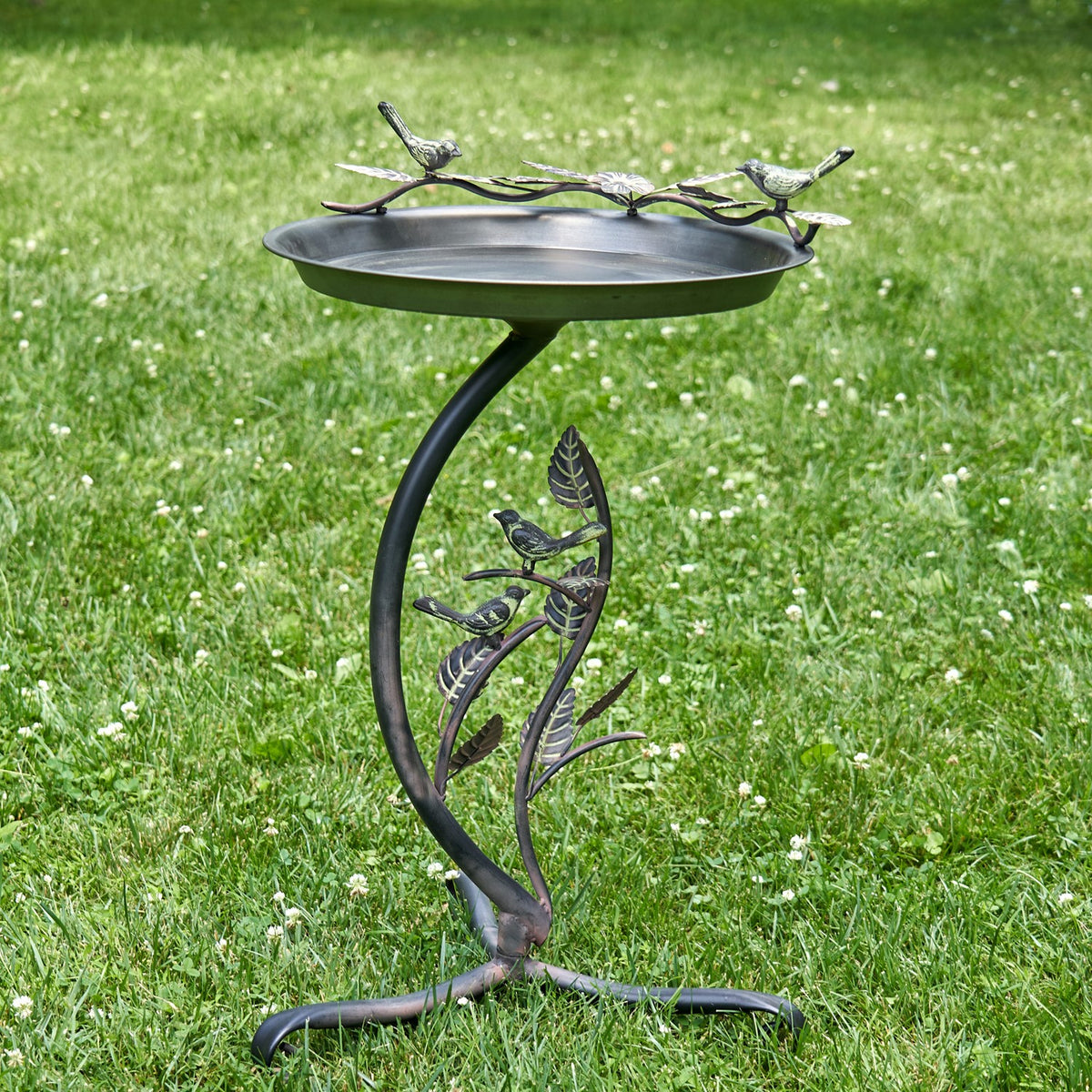 The birdbath and its curved stand with leaf and bird details shown against a grassy lawn.