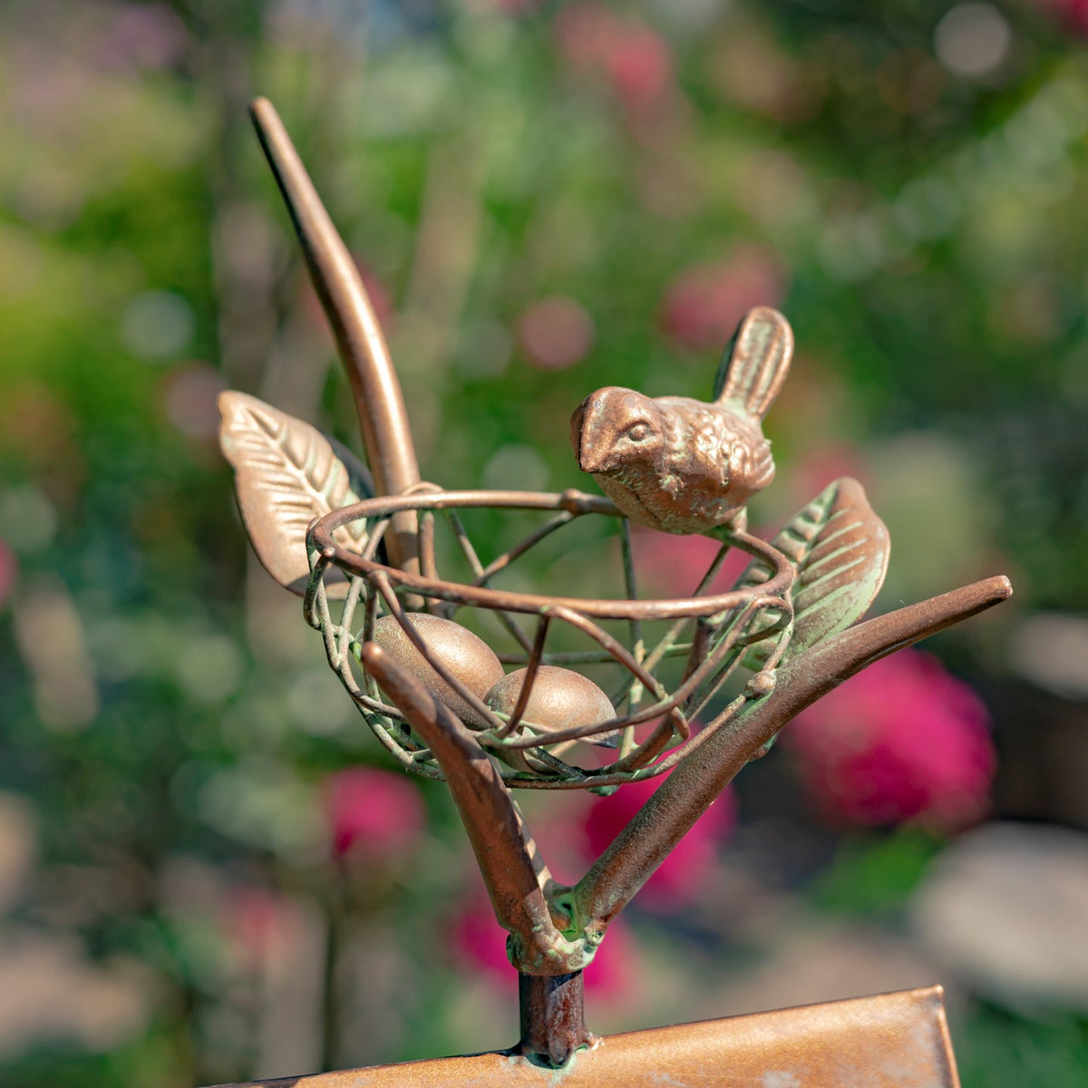 Close-up of the stake’s decorative wire nest, small bird figure, and sculpted metal leaves.