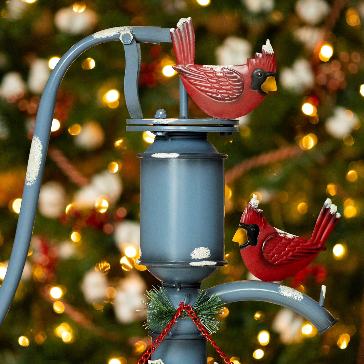 Close-up of the pump's upper section, showing two red cardinal figures and a curved blue spout.