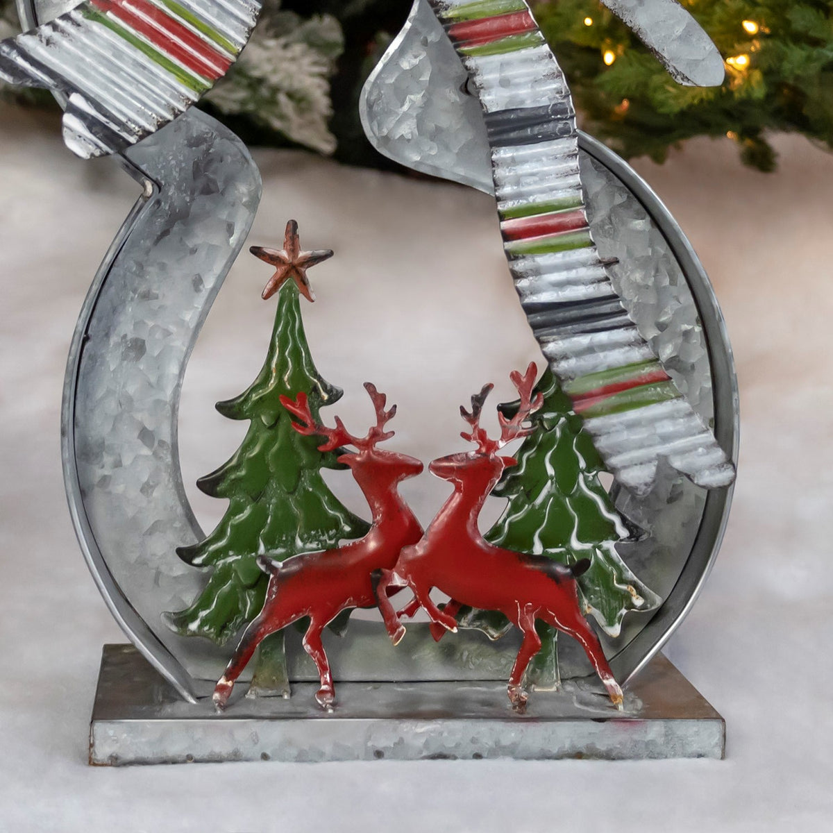Close-up of two red reindeer beneath green Christmas trees inside the snowman’s metal body.