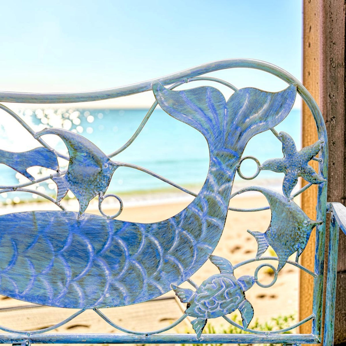 Close-up of the bench back, with a mermaid tail, fish, and wave-shaped metal scrollwork.
