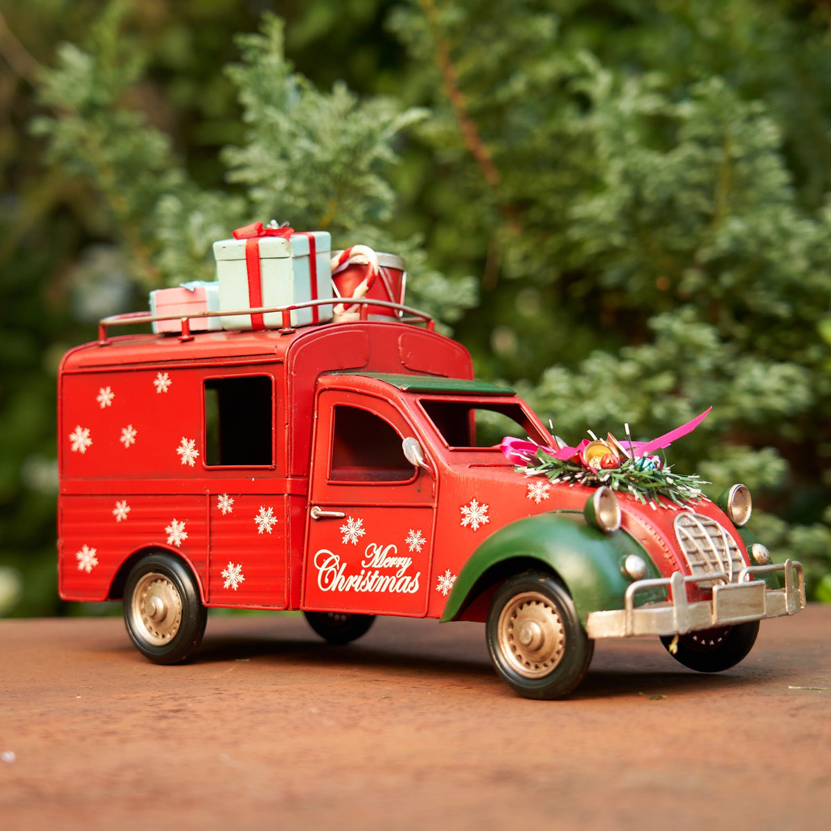 Red Christmas truck with snowflake decorations and a floral hood arrangement, viewed from the other side.