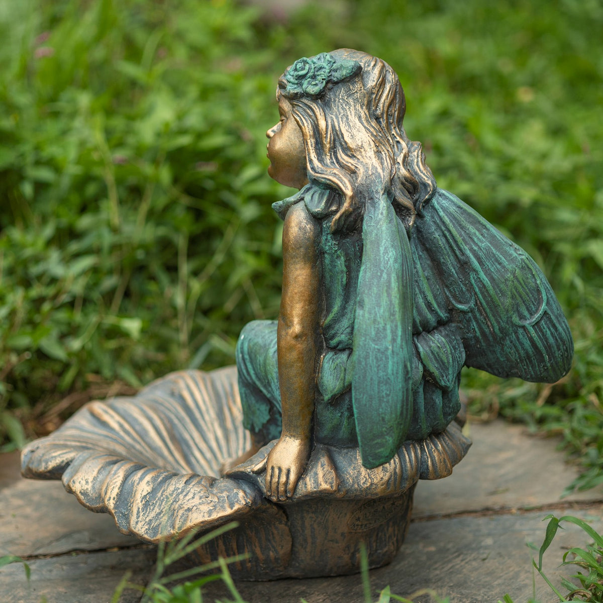 The seated fairy is shown from behind, with detailed wings and a flower-shaped base.