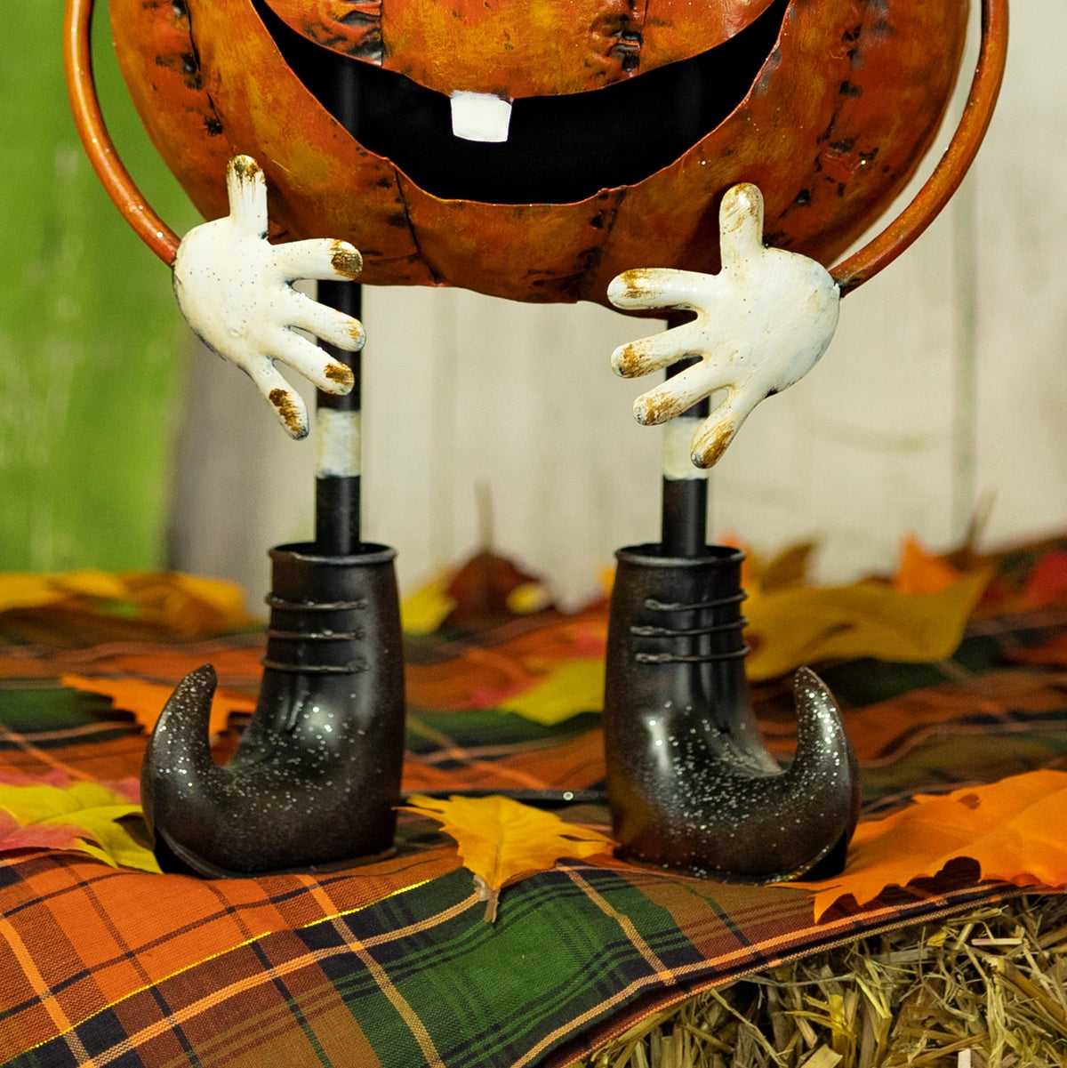 Close view of the figurine's white hands and black boots against an autumn display