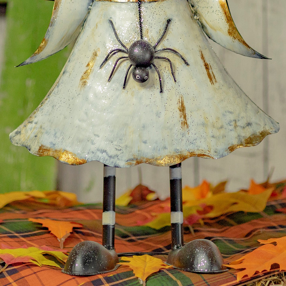 Close view of the white dress, metal legs and feet on a fall leaf display