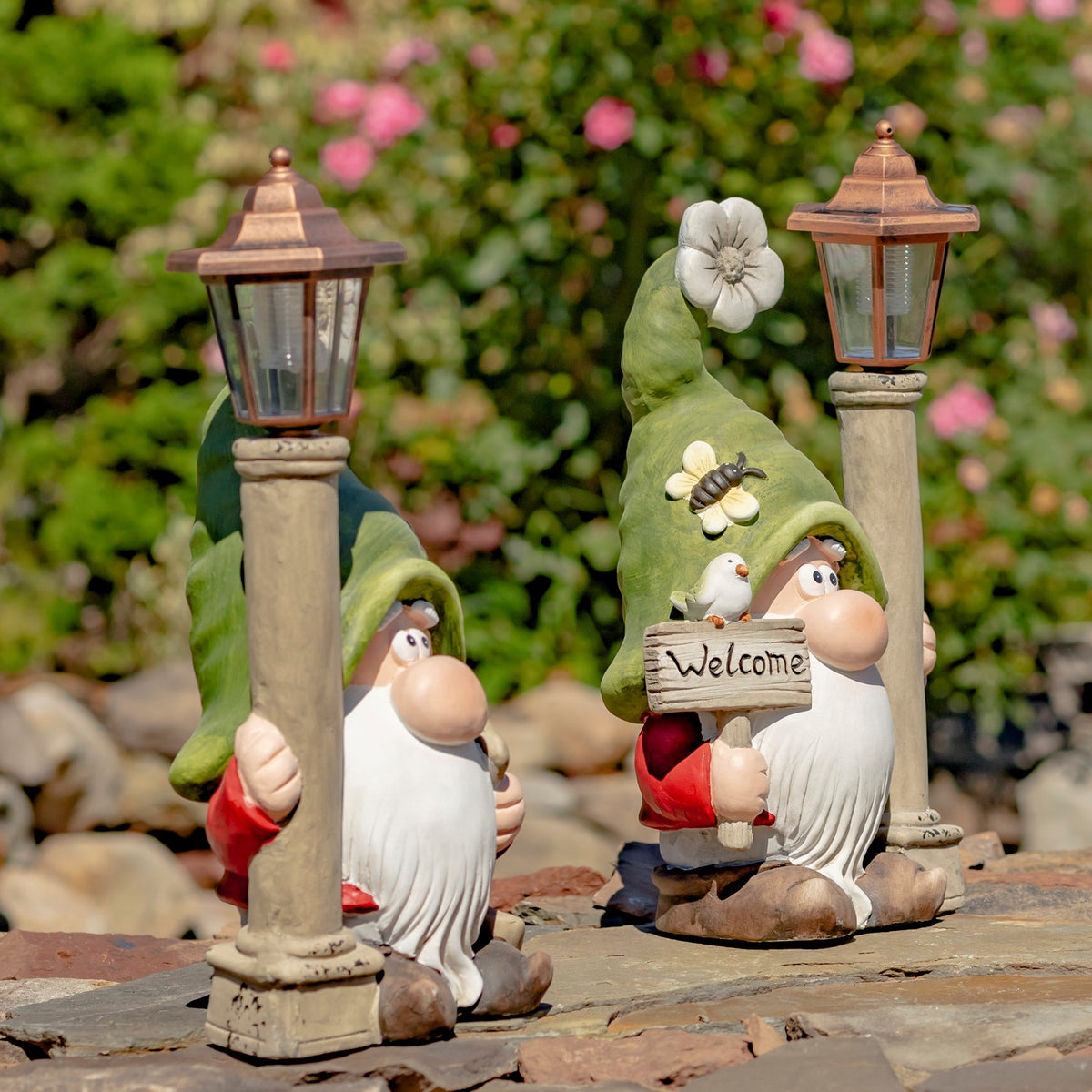Two garden gnomes with solar lanterns viewed from the side in a garden