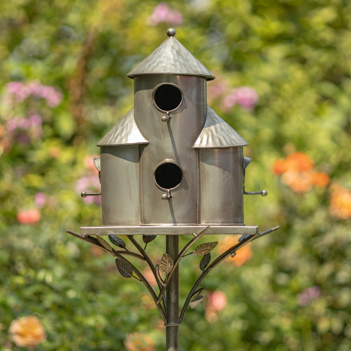 A tall central birdhouse flanked by two shorter ones, each with a conical roof and dark circular entrance.