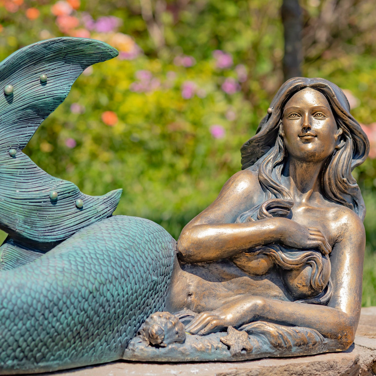 Closer view of the mermaid's face and crossed arms beside her textured teal tail.