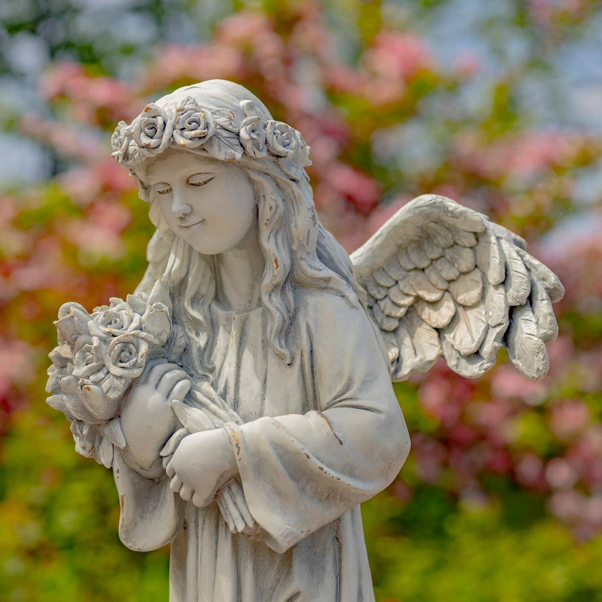 Closer view of the angel holding a cluster of roses, with a large feathered wing behind her.