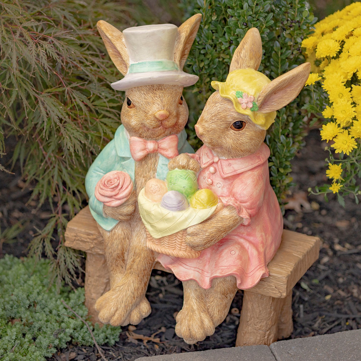 The rabbit couple sits together on a wooden bench, with their full outfits and egg basket visible.