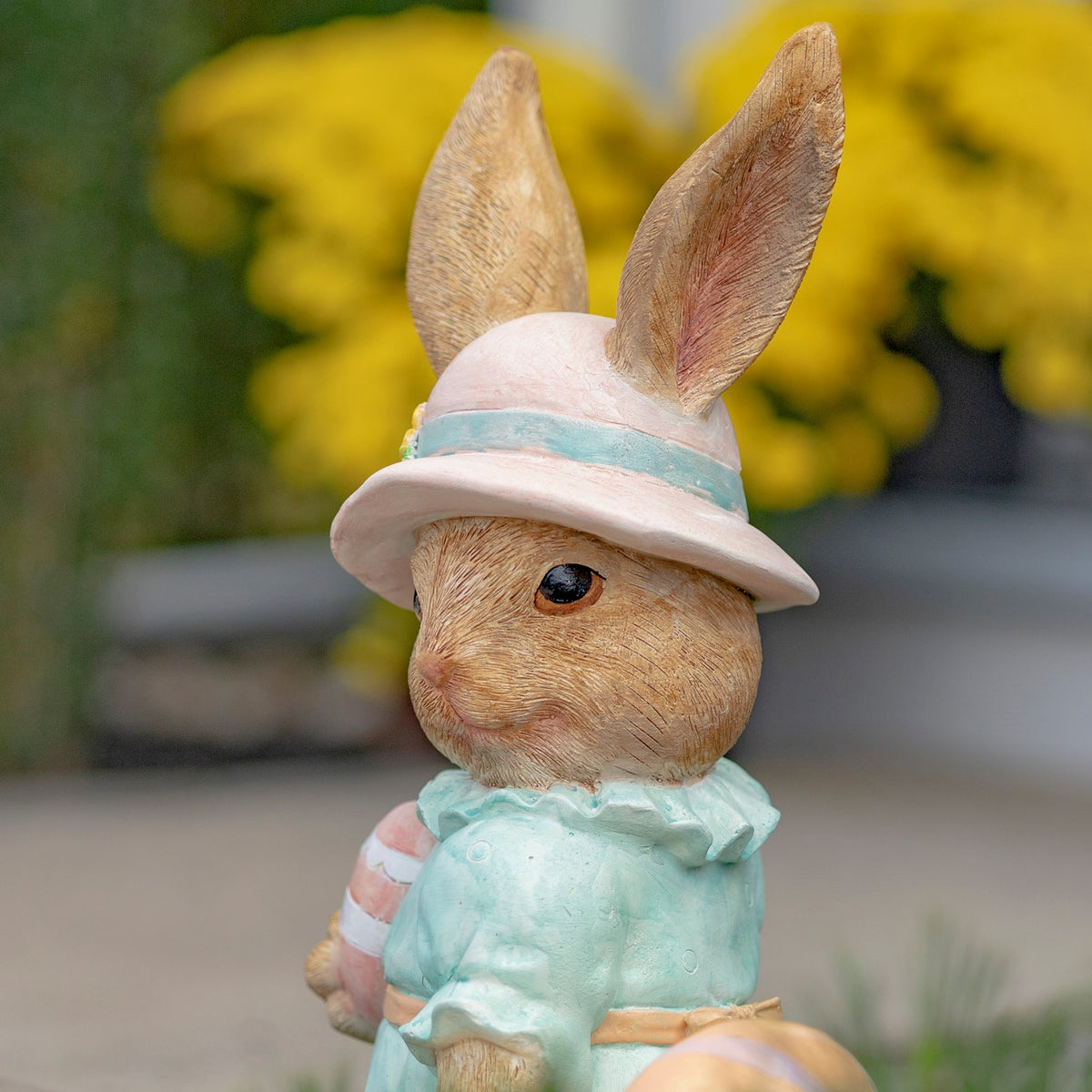 Close-up of the rabbit's textured face, tall ears, and flower-trimmed sun hat.