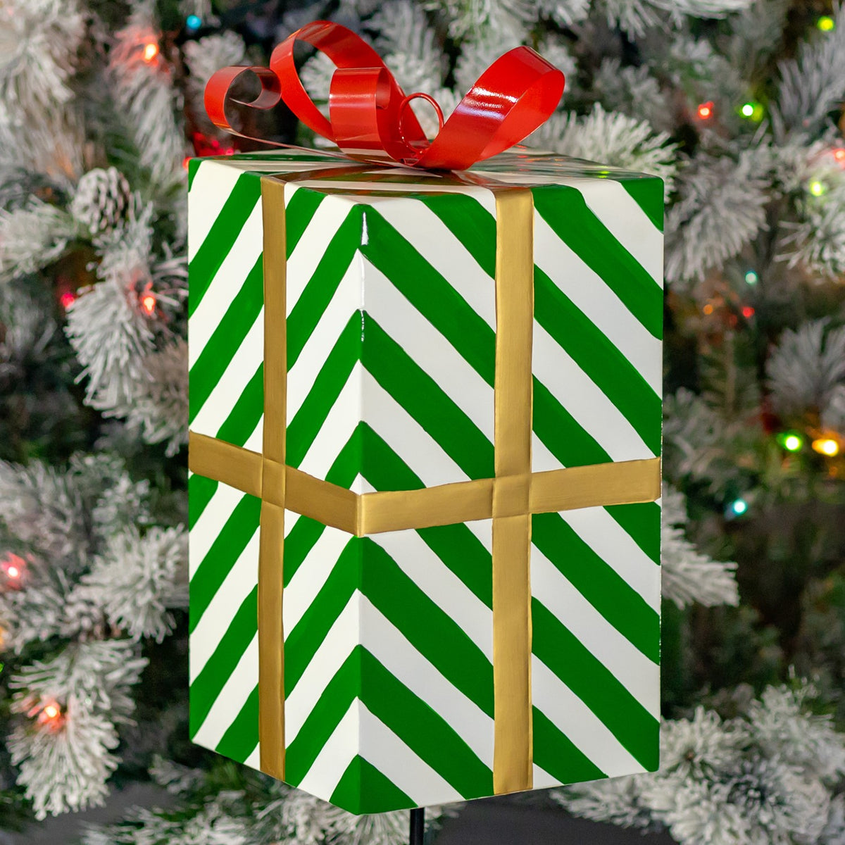 Close view of the box’s green-and-white chevron stripes, gold-colored bands and curled red bow.
