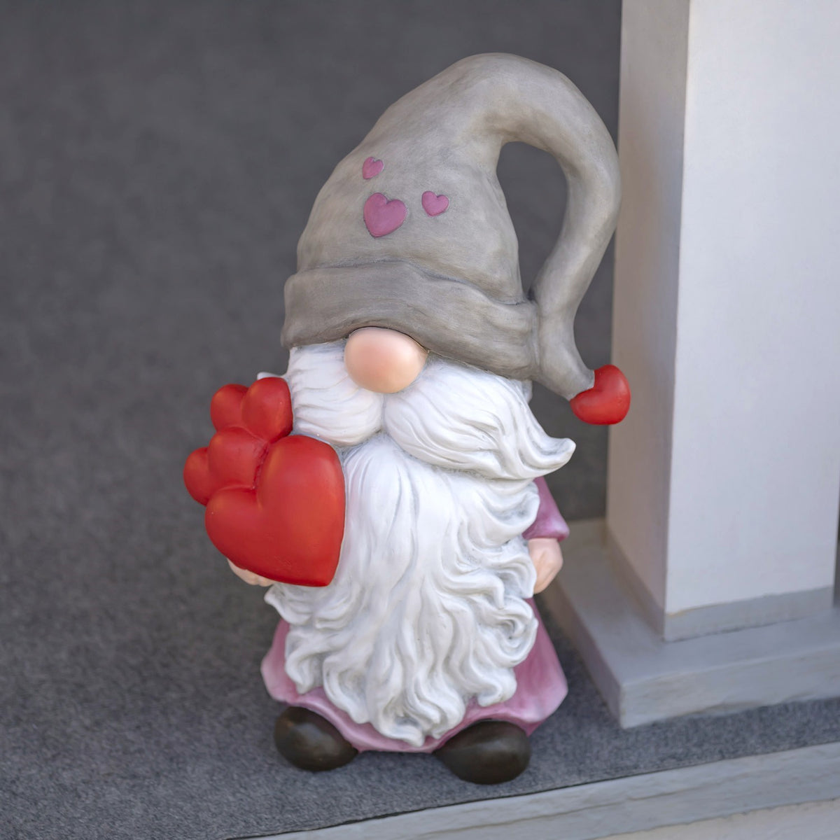 The gnome stands by a porch column, showing its pink tunic, white beard, and heart details.