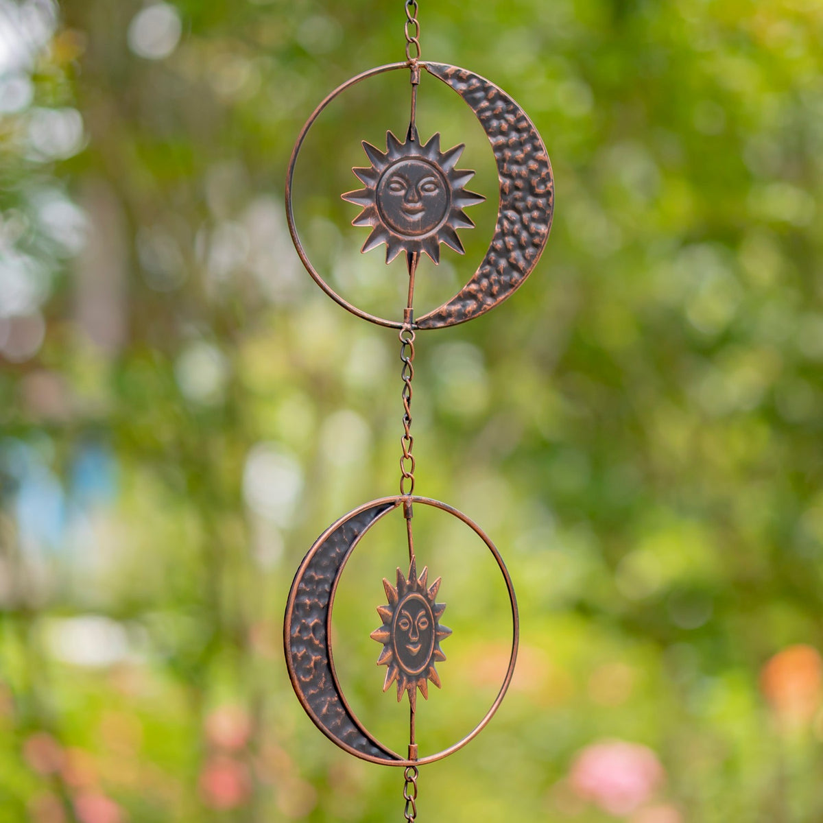 Two antique bronze sun and crescent moon ornaments shown on the hanging chain
