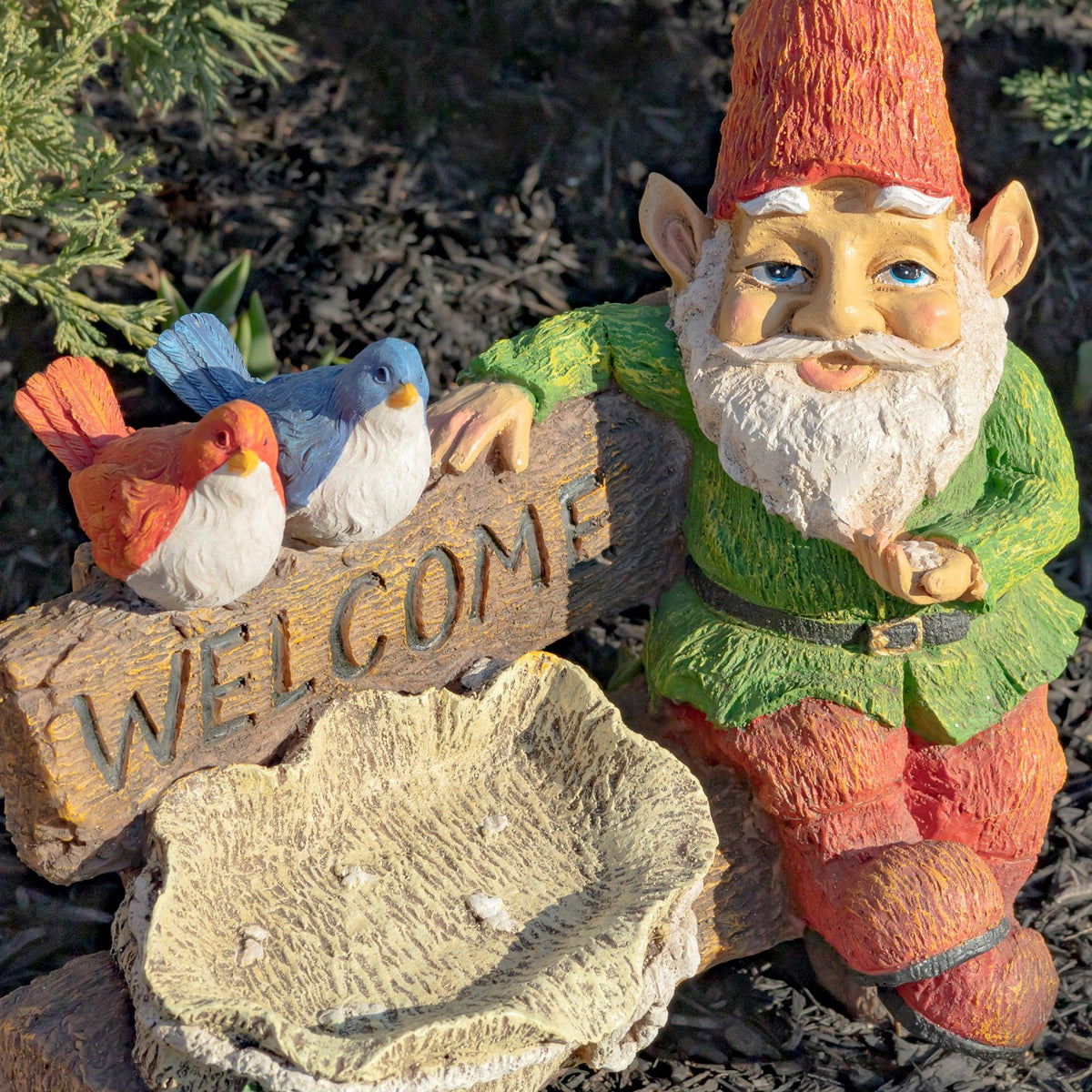 Close view of the gnome's painted face and clothing, with two birds, a sign, and the birdbath in the foreground.