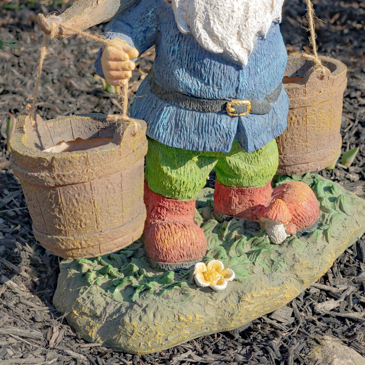 The gnome’s green trousers and boots stand on a leafy base beside two hanging buckets.