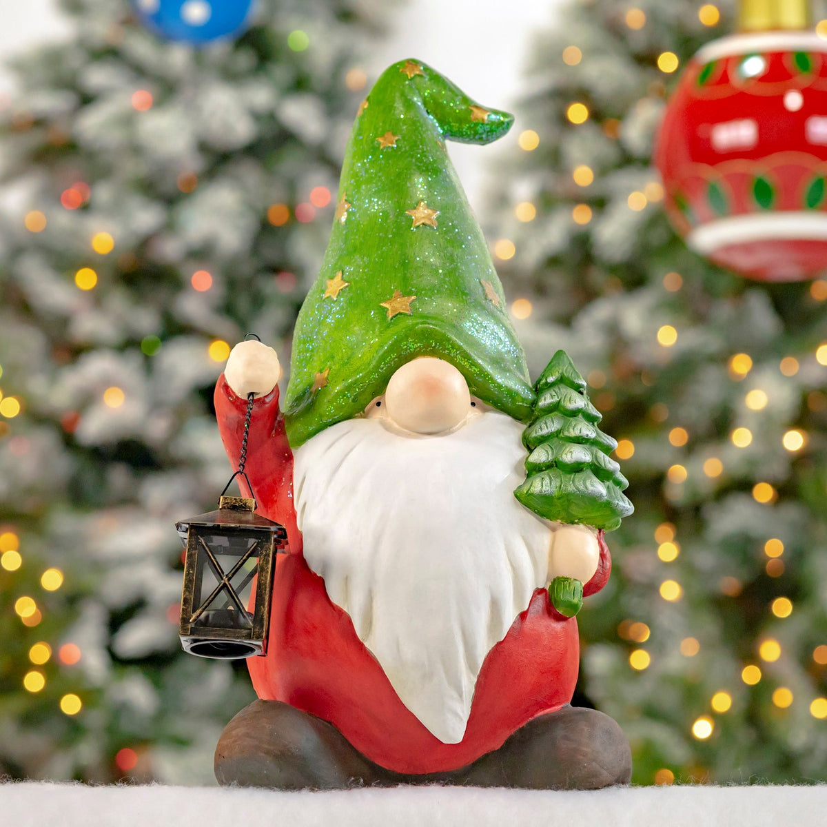 Red-clad gnome in a tall green hat holding a lantern beside a tree