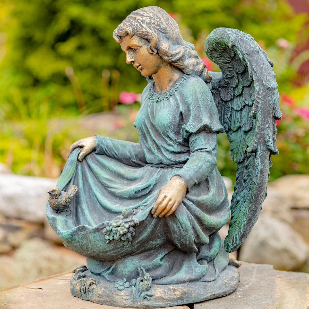 Side angle showing the kneeling figure, draped skirt, raised wing, and decorated base.