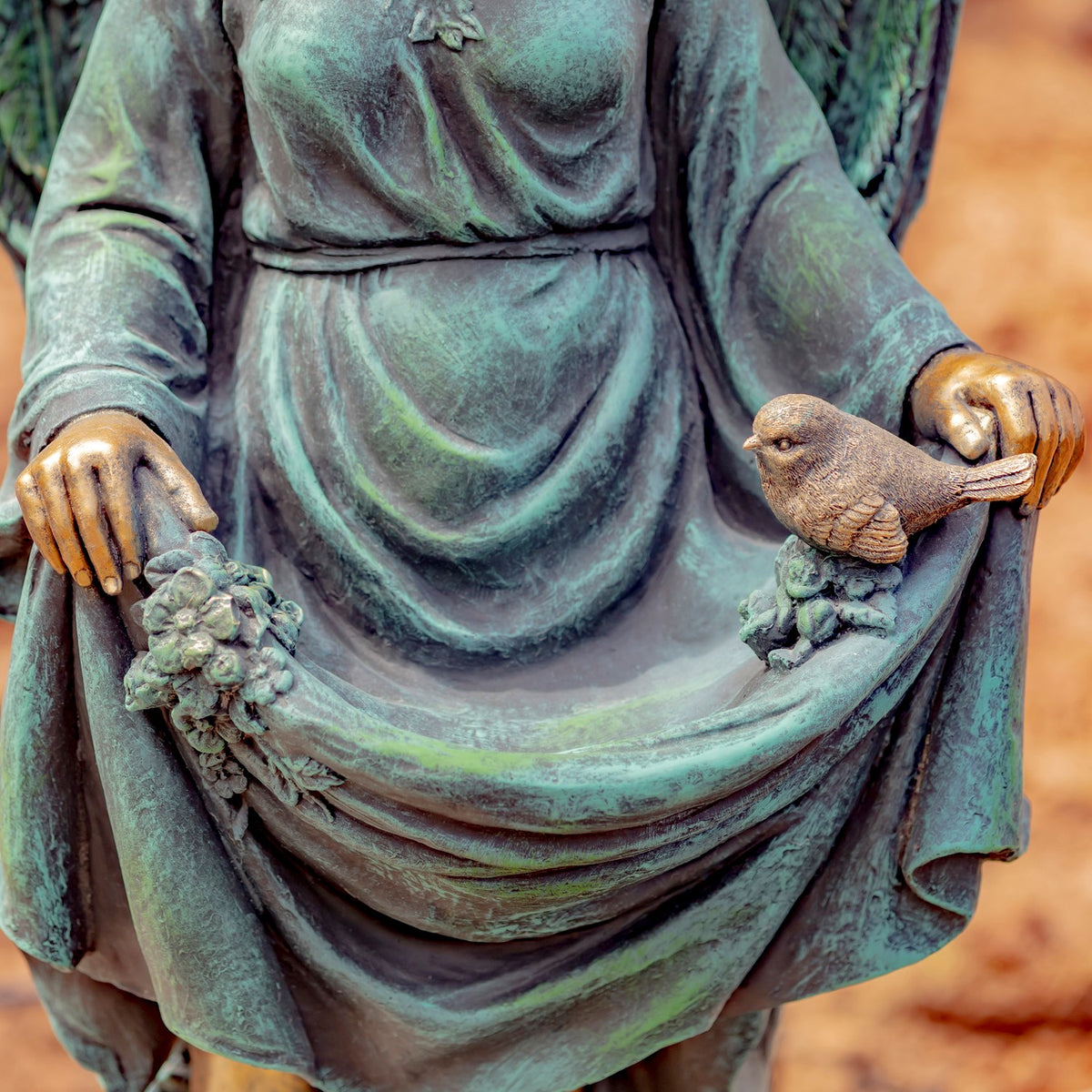 Close-up of the statue’s hands holding the draped skirt, with a small bird perched on the fabric.