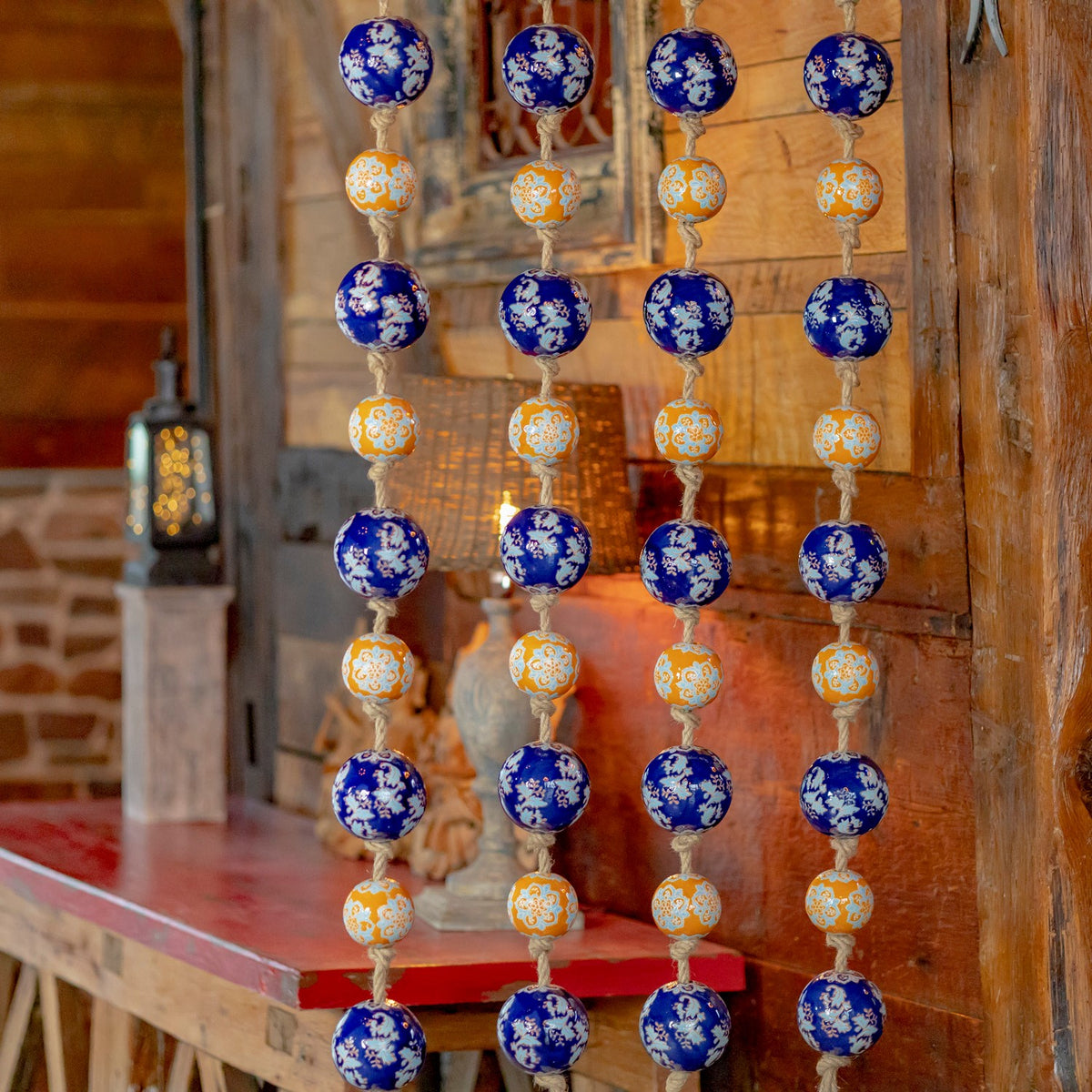 Four vertical strands of blue and orange patterned balls displayed beside a wooden table.