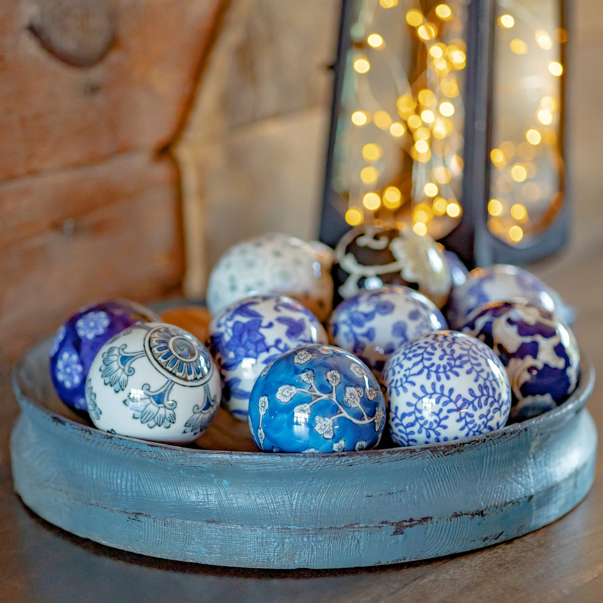 Blue-and-white ceramic balls with varied floral designs, with a lantern softly blurred behind them.