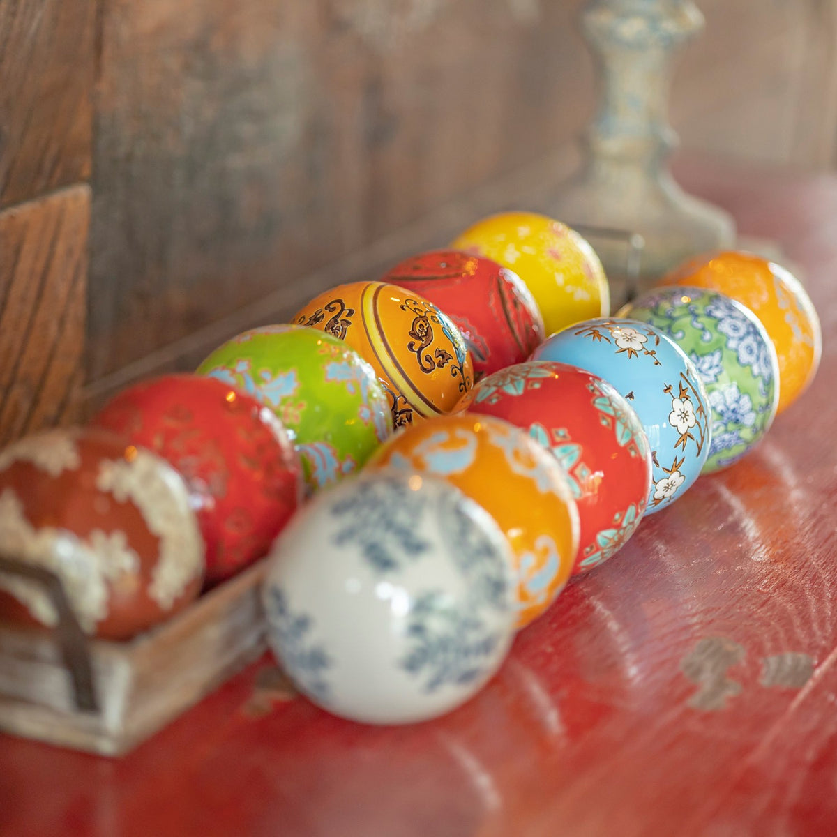 Patterned ceramic balls in varied bright colors arranged in a shallow tray, with the nearest balls softly out of focus.