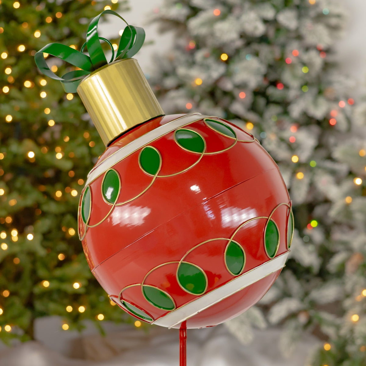 The ornament from another angle, showing its glossy red surface, looping green accents and gold edging.