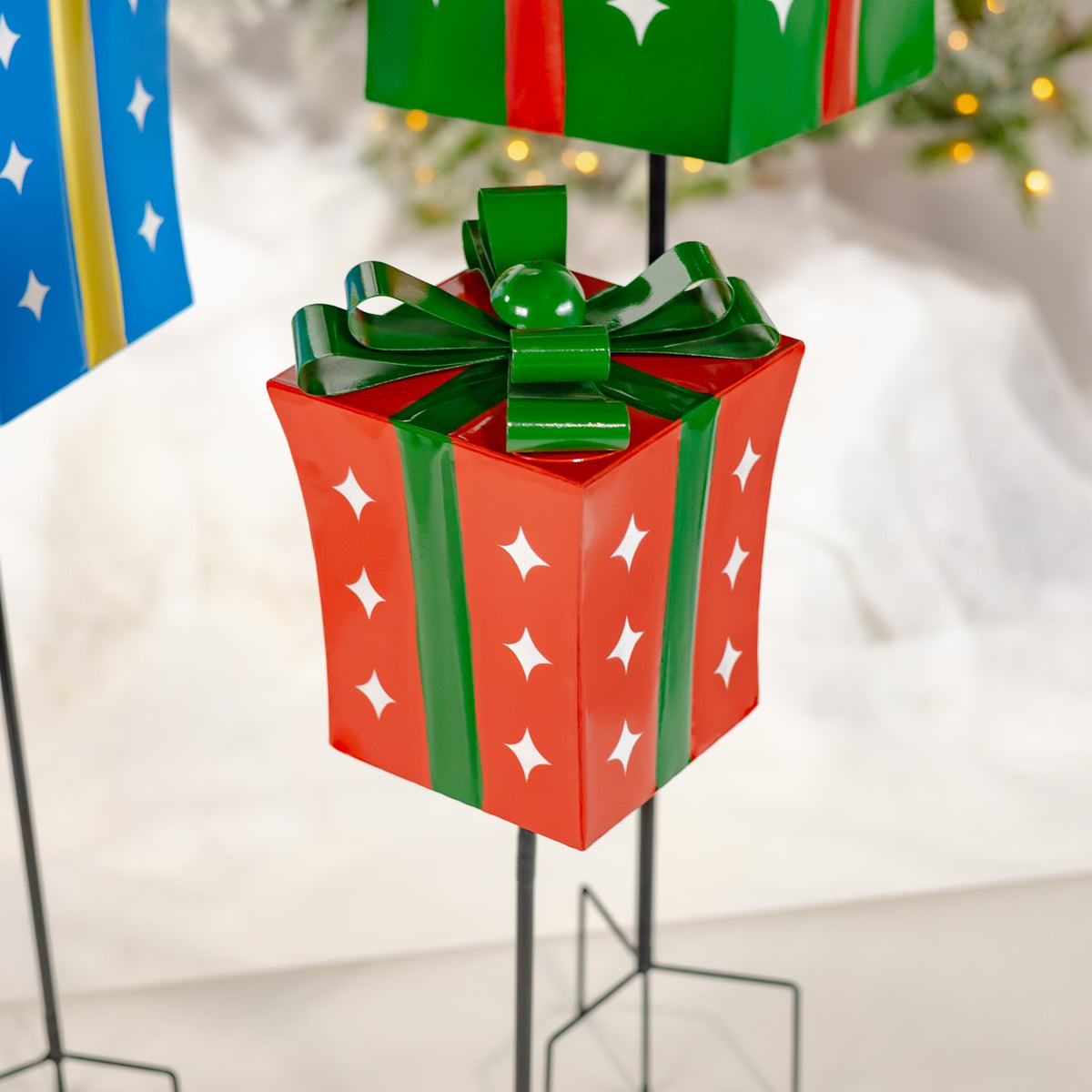 Close-up of the red gift-box stake, showing its glossy green bow and white star cutouts.