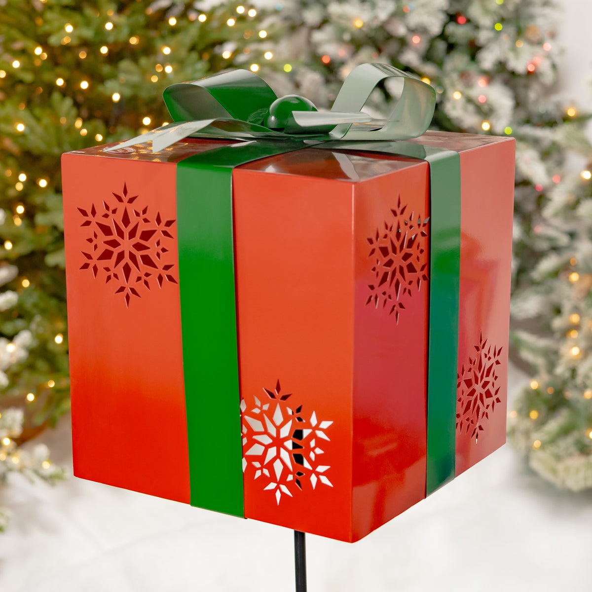 Close-up of a red gift-box stake with green ribbon and snowflake cutouts