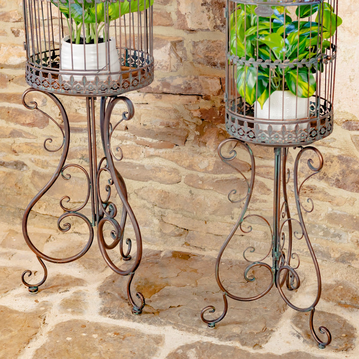 Close view of the dark birdcage planters’ decorative bases and curled metal stands.