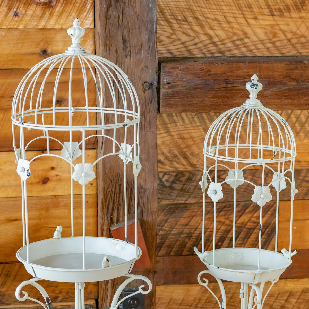 Closer view of the white birdcage planters, showing domed wire tops and flower-shaped ornaments.