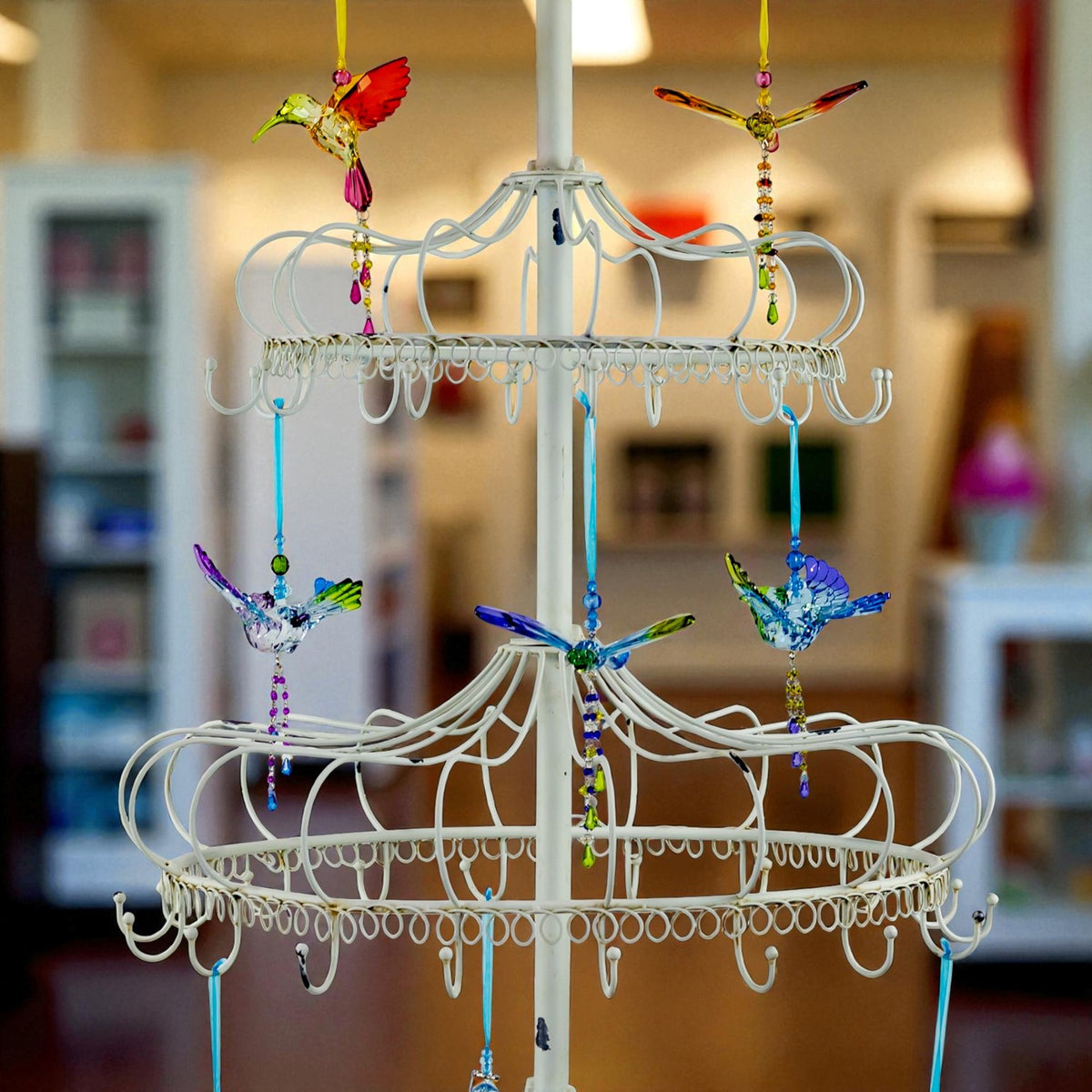 Two ornate circular tiers with dangling hooks and bright bird ornaments suspended from colorful strings.