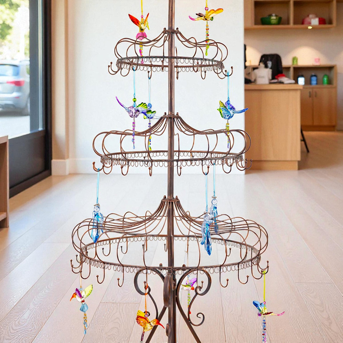 Three levels of curved metal display rings hold dangling colorful bird ornaments against a shop backdrop.
