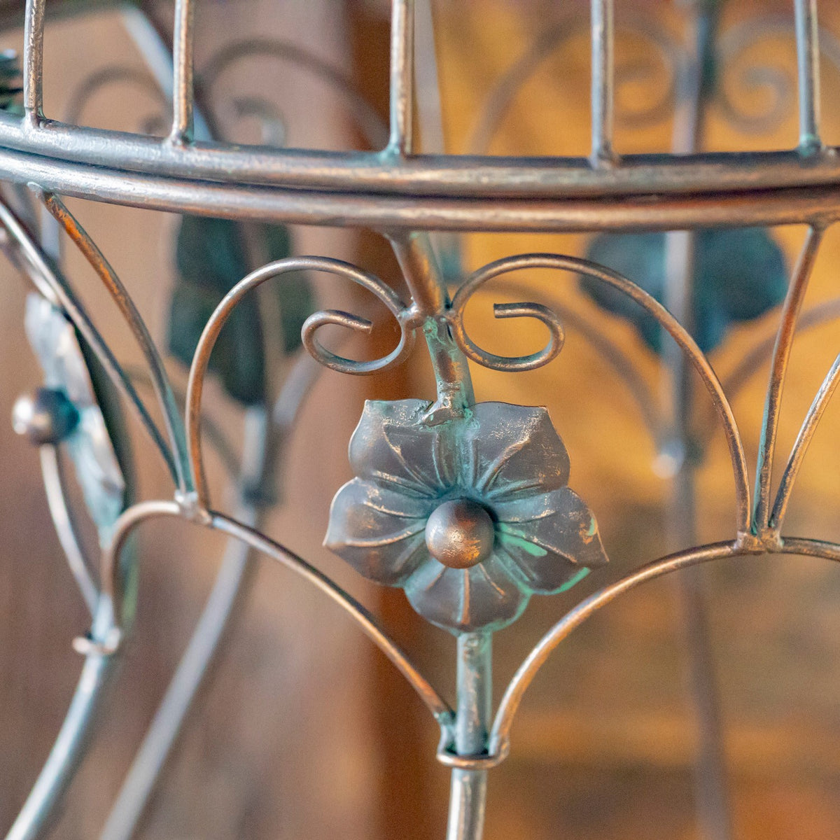 Metal flower ornament and curled bars beneath the rounded cage rim.