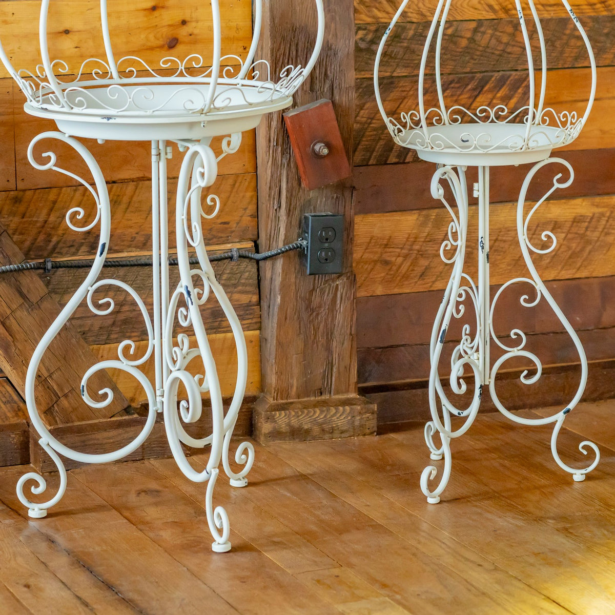 Close view of the decorative curled iron legs on two white plant stands
