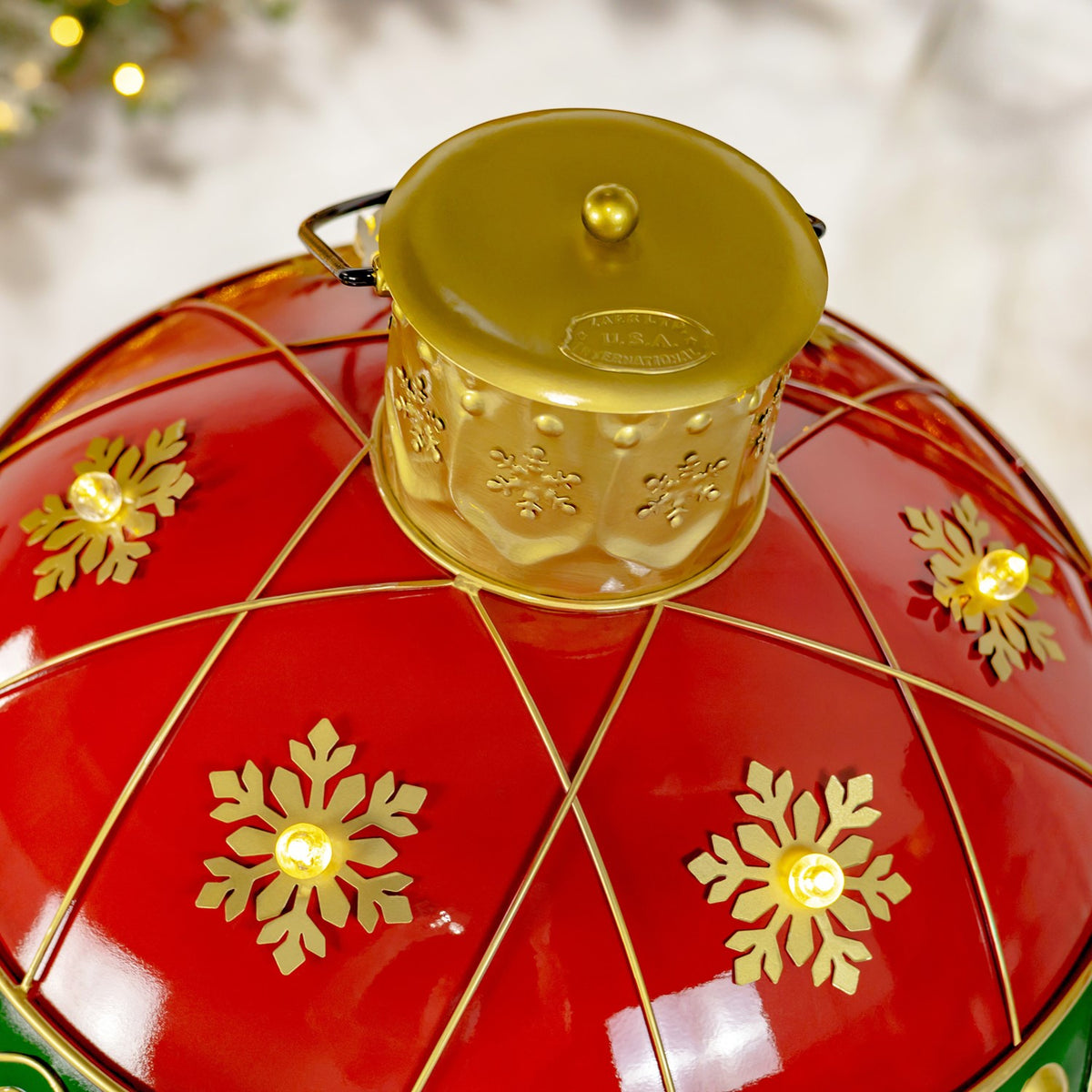 Close-up of the gold ornament cap and illuminated snowflakes on its red segmented top.