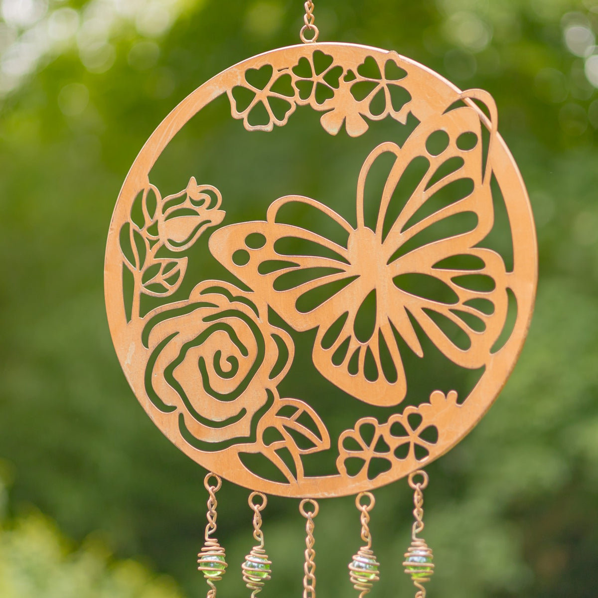 Close view of a copper-finish circular wind chime with butterfly and flower cutouts