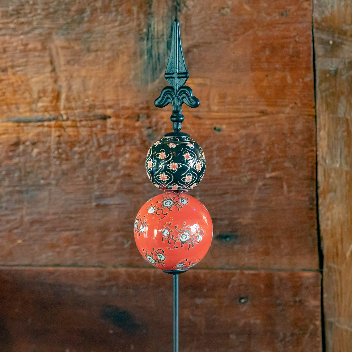 Coral and dark patterned ceramic spheres with a pointed iron finial