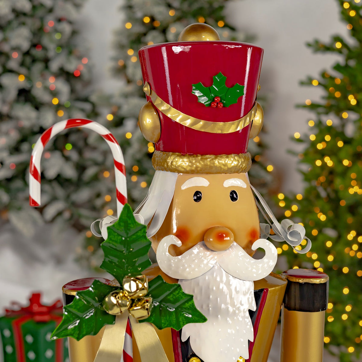 Close-up of the nutcracker’s red hat, holly decoration, curled white mustache, beard, and candy cane.