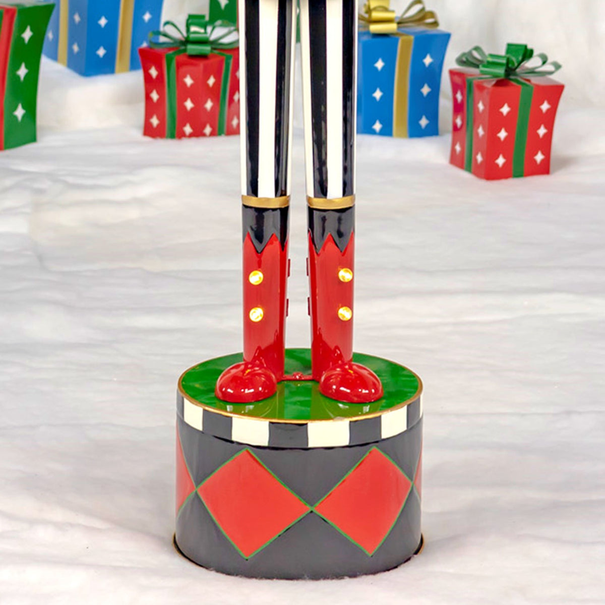 The nutcracker’s striped legs and red boots stand on a green-topped base with diamond patterns.