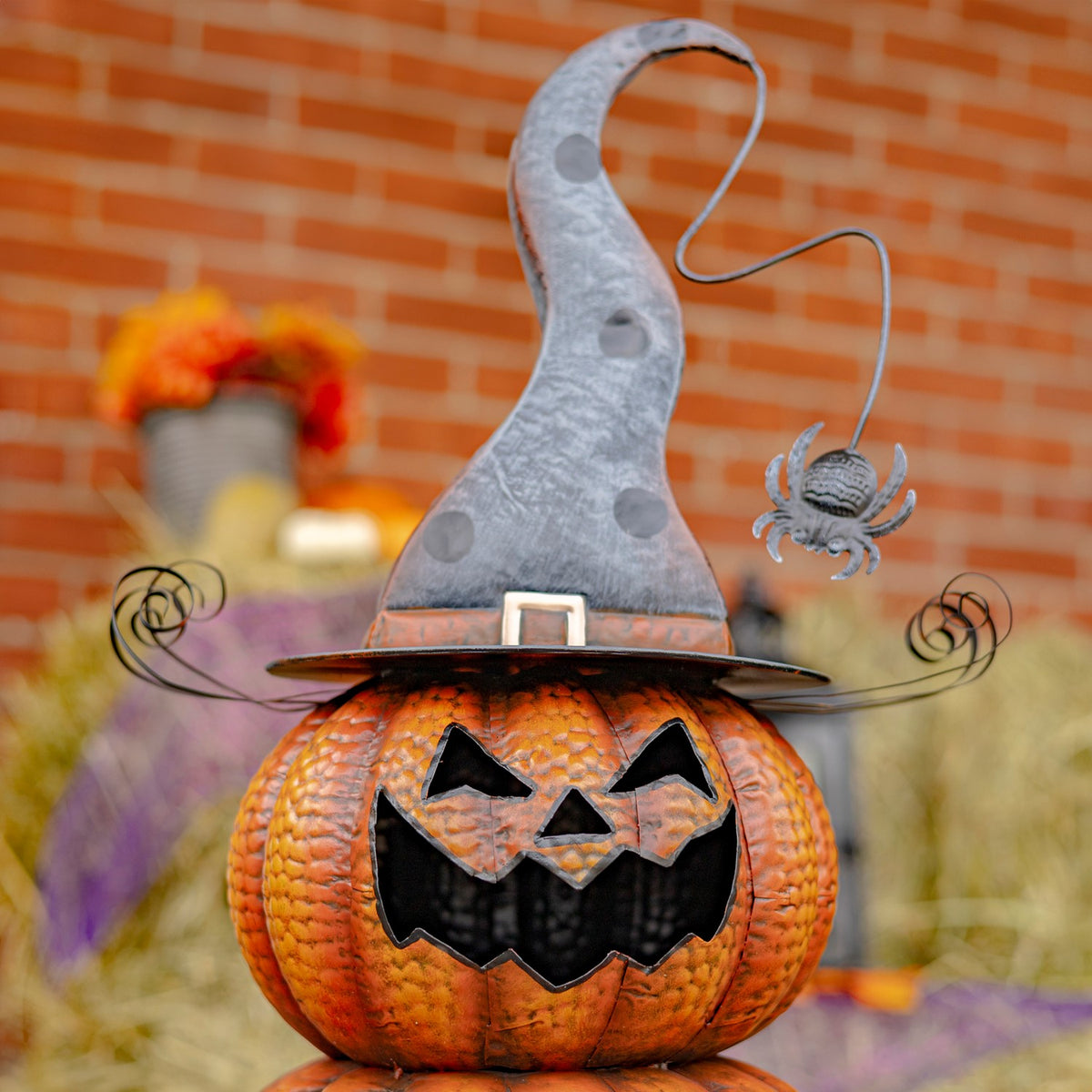 The top jack-o’-lantern wears a weathered gray pointed hat with curled wire trim and a small hanging spider.