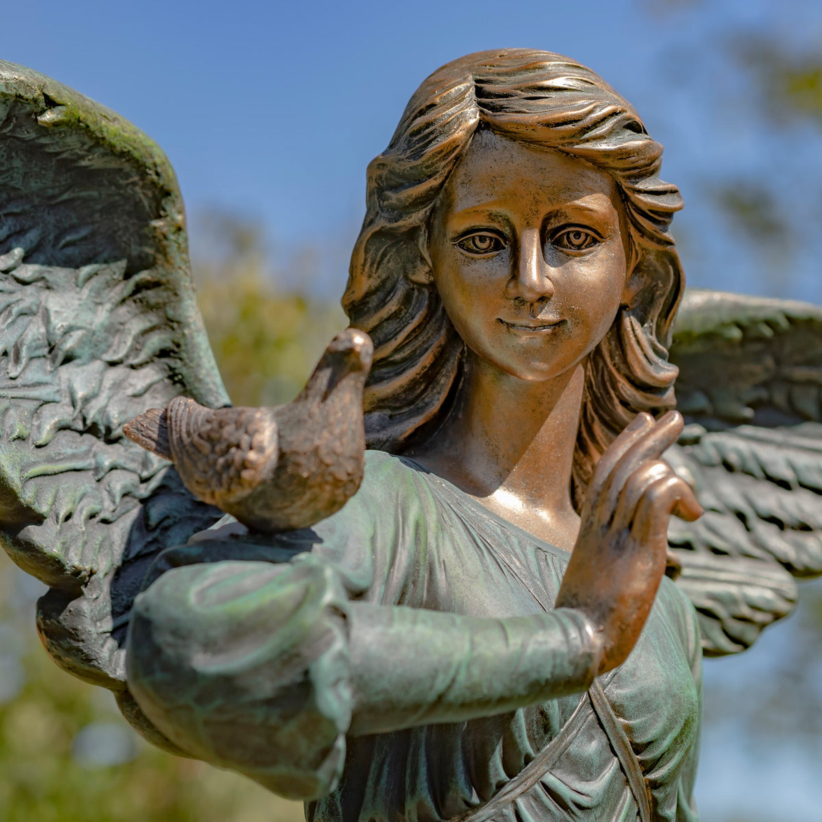 Close-up of the angel’s face and raised hand beside a small bird, with part of one wing visible.
