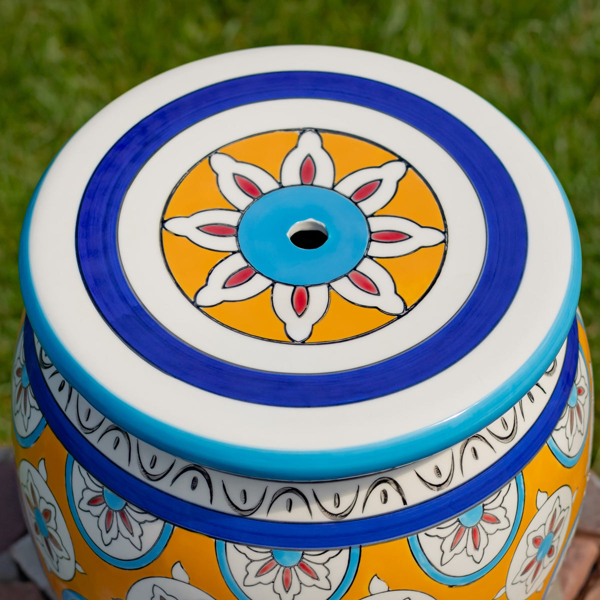 Close-up of the stool’s round top, with a blue, white, and yellow flower design and a small center opening.