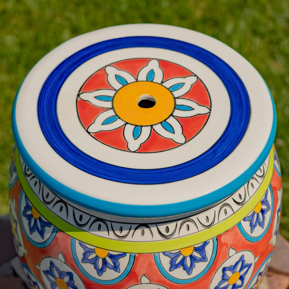 The stool's round top has concentric blue and white rings around a colorful flower design.