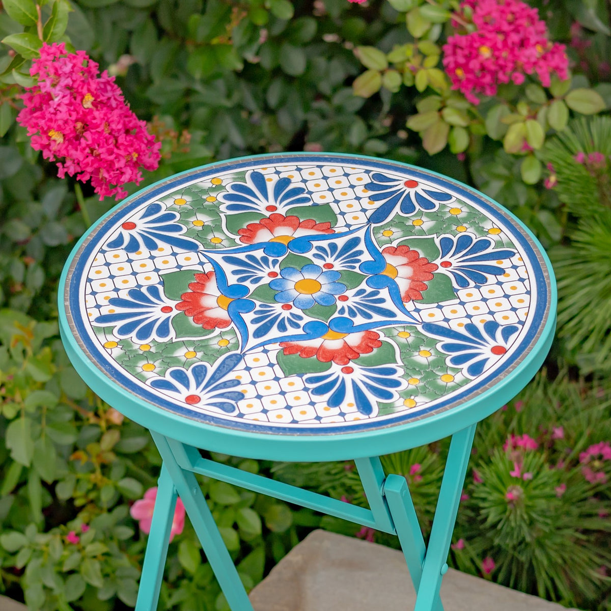 Close-up of the round tabletop’s blue, green, red, and white floral mosaic pattern.