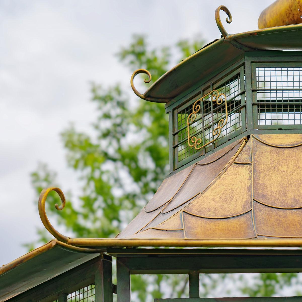Angled view of the layered gold roof, curled metal finials and green gridded upper panels.