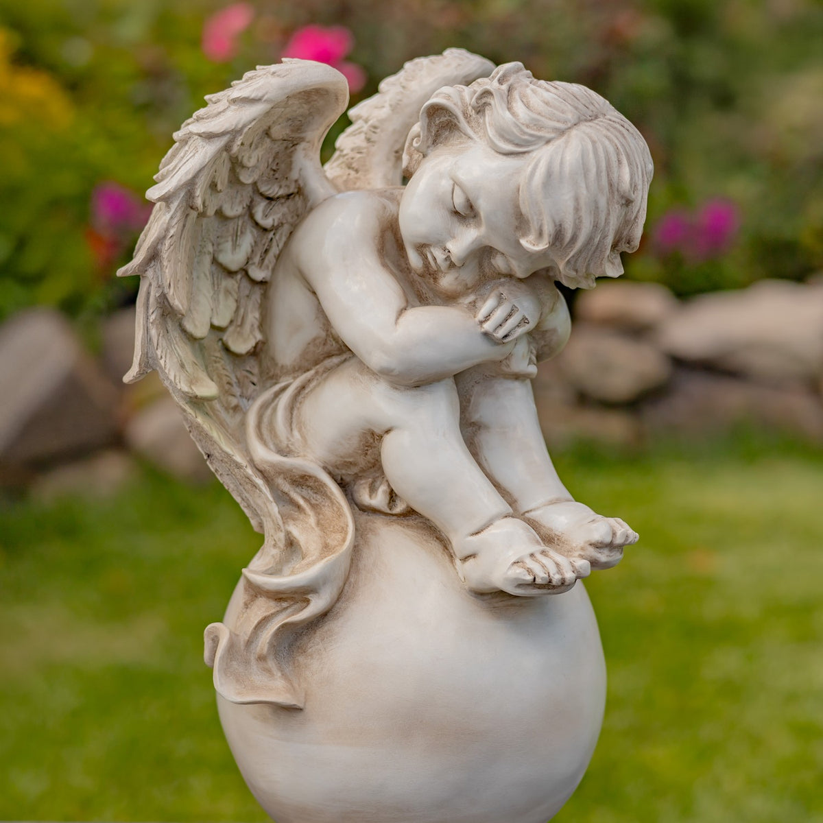 Angled close-up of a cherub leaning forward on a globe pedestal