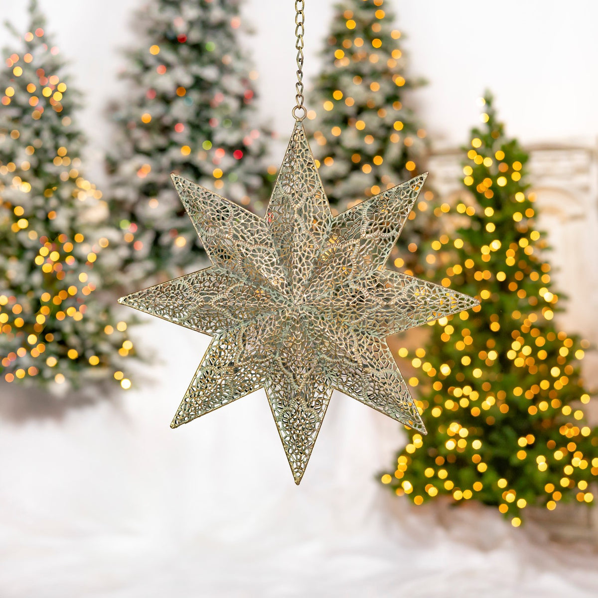 A three-dimensional gold star ornament hangs at an angle, showing its layered openwork construction.